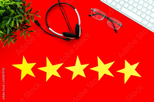 Customer support and experience concept. Five stars near headset on red office desk top-down copy space
