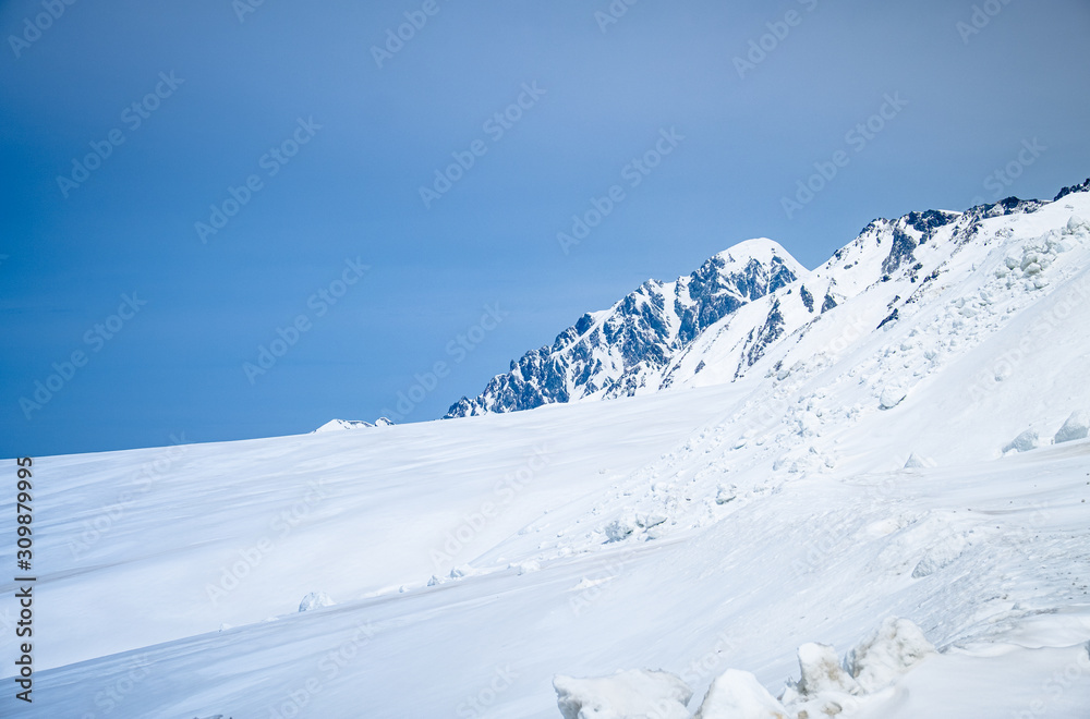 close up top of white snow mountain view, snow covered beautiful landscape on blue sky background space.Famous place of snow mountains of Japan Alps in Tateyama Kurobe alpineat Toyama, Japan. 
