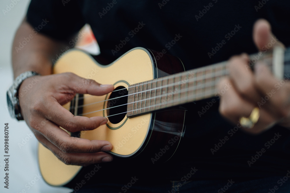 Fototapeta premium Close up man's hands playing the ukulele, concept ralax or artist.