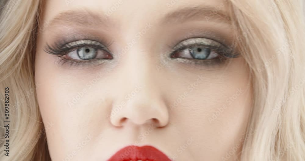 Close up shot of a beautiful caucasian girl wearing bright make up staring at camera with eyes with blue iris 4k footage Close up shot of a beautiful caucasian girl wearing bright make up staring at camera with eyes with blue iris 4k footage