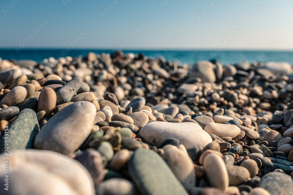 beach with sea pebbles close up on blue sky background. The concept: joy, happiness, positivity, relax, vacation, tourism. beach with sea pebbles close up on blue sky background. The concept: joy, happiness, positivity, relax, vacation, tourism.