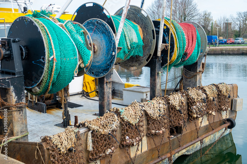 The rear side of a fishing boat in the harbor, showing the nets and chains