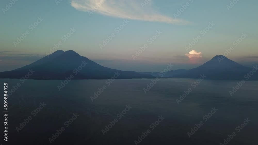 Cinematic aerial shot of Atitlan lake on a sunrise, with huge Volcanoes on the background in Guatemala region of Sololá. 4k drone.