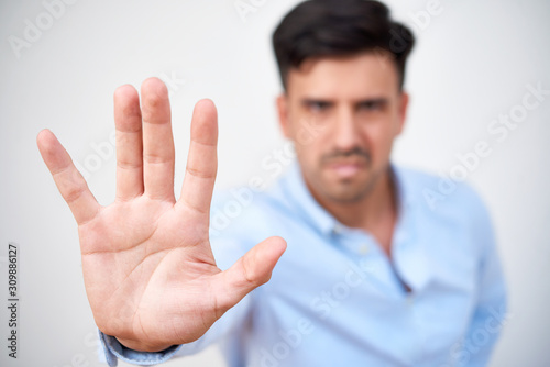Angry young businessman showing stop gesture, focus on palm