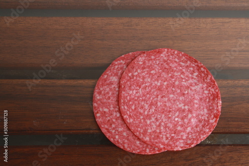 slices of salami on wooden background