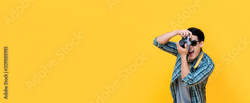 Excited tourist photographer taking photo with camera on yellow banner background