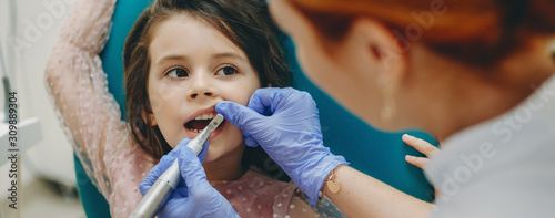 Lovely little girl having a tooth examination while sitting in a stomatology char in a pediatric stomatology. photo