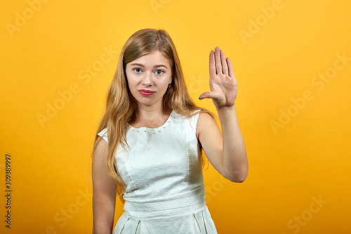 Caucasian young woman keeping finger up, doing bla bla bla gesture, looking serious over isolated orange background wearing white shirt. Lifestyle concept