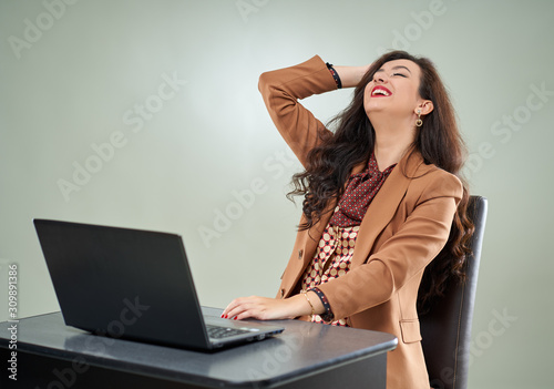 Amused business woman laughing reading on laptop