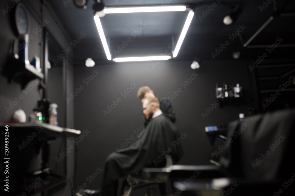 Blurred photo of a barber shop room in black style and lamps.