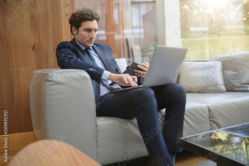 Businessman connected on laptop in hotel lounge © goodluz