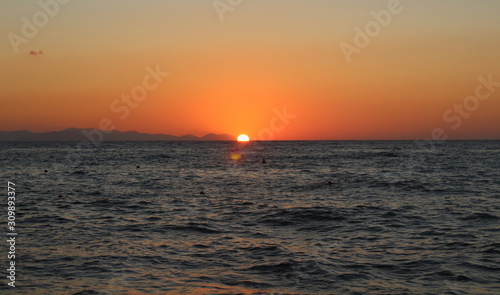 the sun setting behind the promontory with the sea in the foreground © massimo