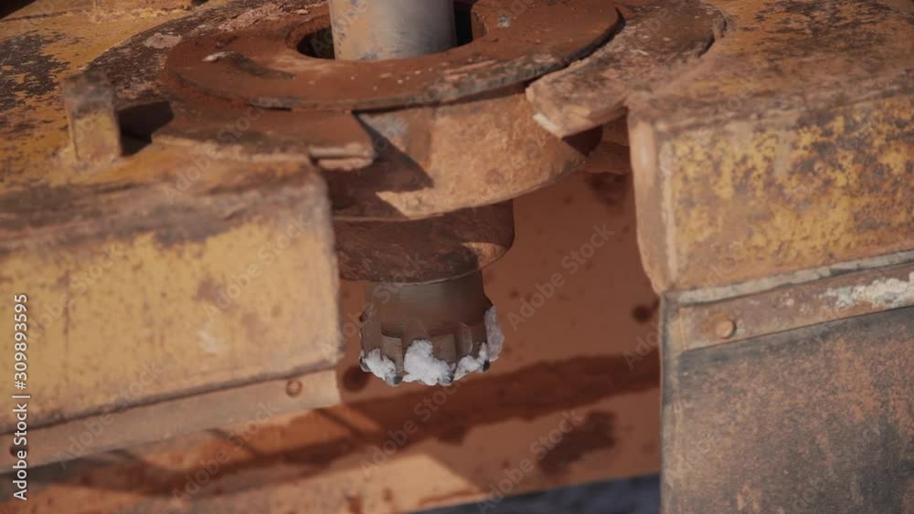 Turning equipment in working process on production site of oil factory. Closeup view of old drilling tool rotate and work on manufacturing area of gas fuel plant. Concept: business, technology