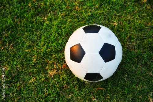 football (soccer) on green grass and sunset light. 