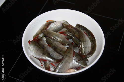 Peeled raw fish perch in a white plate stands on a black table