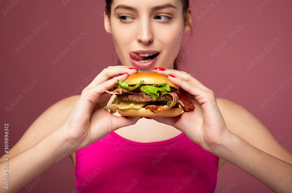 Hungry woman holding big burger. Hungry woman holding big burger.