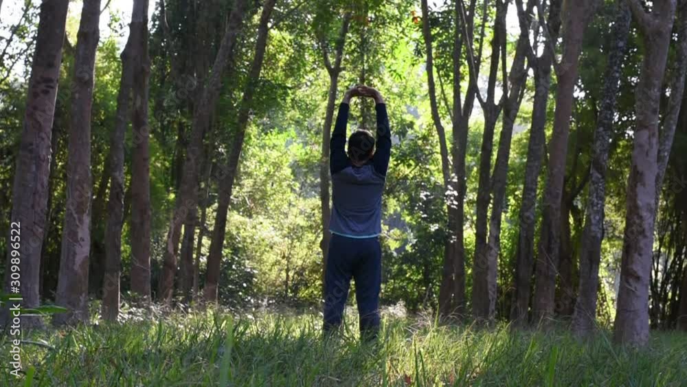 A man is exercises between green forest tree, Relaxing with the dark green tree A man is exercises between green forest tree, Relaxing with the dark green tree