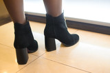 Girl in fashionable black boots in a shopping center on a bright tile, demonstrative photos