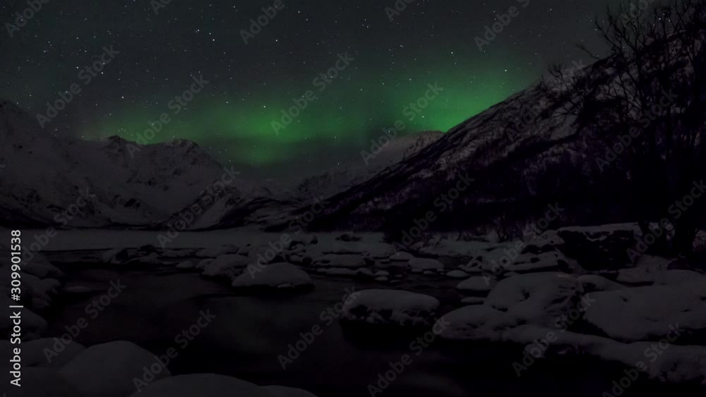 Time Lapse of Aurora Borealis, Northern Lights, and stars in Tromsoe, Norway. River in foreground and snowy mountains in background. Time Lapse of Aurora Borealis, Northern Lights, and stars in Tromsoe, Norway. River in foreground and snowy mountains in background.