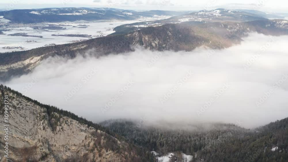 Aerial of low hanging clouds in snow covered mountain pass Aerial of low hanging clouds in snow covered mountain pass
