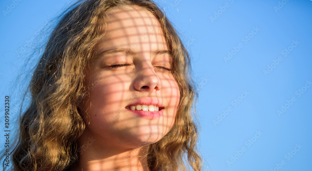 Sunscreen concept. Child pleased with warm sunlight looks relaxed blue sky background. Take care skin put sunscreen cosmetics. Girl kid relaxing outdoors. Take care. Uv filter sunscreen. Summer care Sunscreen concept. Child pleased with warm sunlight looks relaxed blue sky background. Take care skin put sunscreen cosmetics. Girl kid relaxing outdoors. Take care. Uv filter sunscreen. Summer care