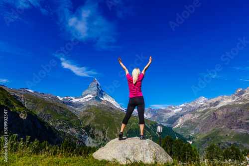 Young girl holds hands up against the sky and mountain