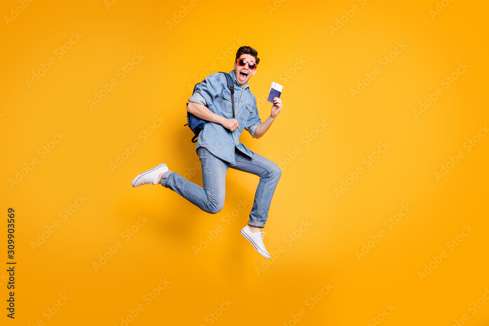 Side profile full length body size photo of screaming crazy man holding passport ticket with hands in white footwear near empty space isolated vivid yellow color background