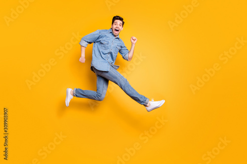 Full length body size view of his he nice attractive cheerful cheery overjoyed guy jumping running having fun isolated over bright vivid shine vibrant yellow color background