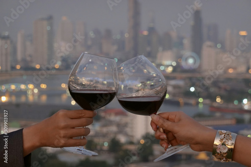  Romantic couple or friendship which happy moment relaxing ,red,wineglass,celebration on the rooftop in the night with bokeh background