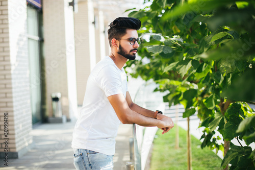 Young Indian man smiling with arms on handsrail at rooftop of business center photo