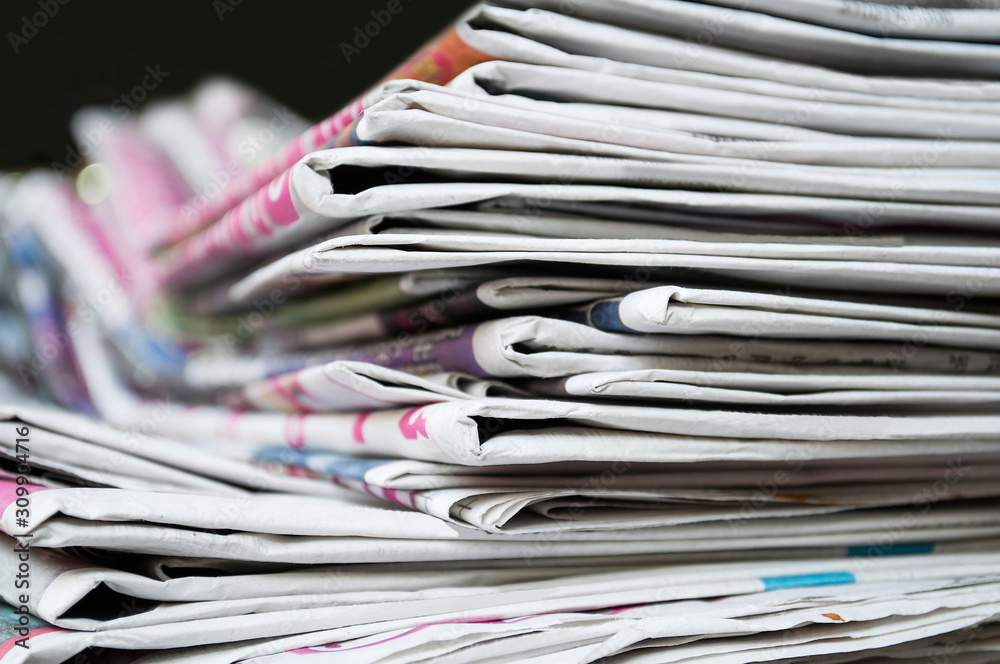 Newspapers folded and stacked on the table dark background. Closeup newspaper and selective focus image. Newspapers folded and stacked on the table dark background. Closeup newspaper and selective focus image.