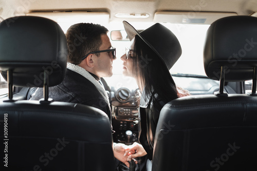 Happy Traveling Couple Dressed in Black Stylish Clothes Enjoying a Road Trip Sitting Inside the Car, Vacation Concept