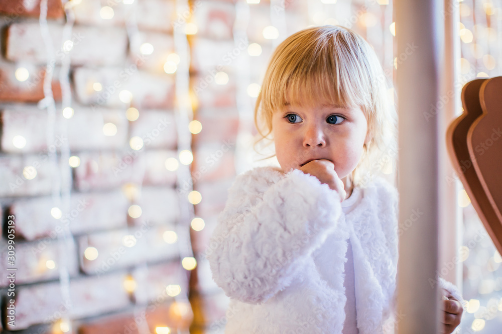 Fototapeta premium Little girl staying near carousel Merry-go-round with lights on a background