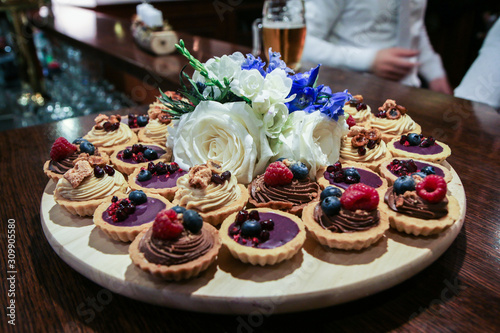 The detail of the sweet cupcakes with cream and fruits prepared for the wedding after party. 