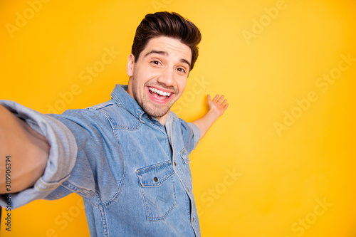 Photo of cheerful positive attractive man welcoming you to come to empty space behind him taking selfie isolated vivid color background photo
