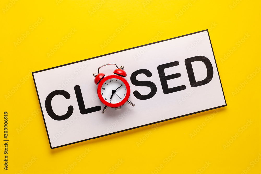 Closed sign with alarm clock on yellow Closed sign with alarm clock on yellow