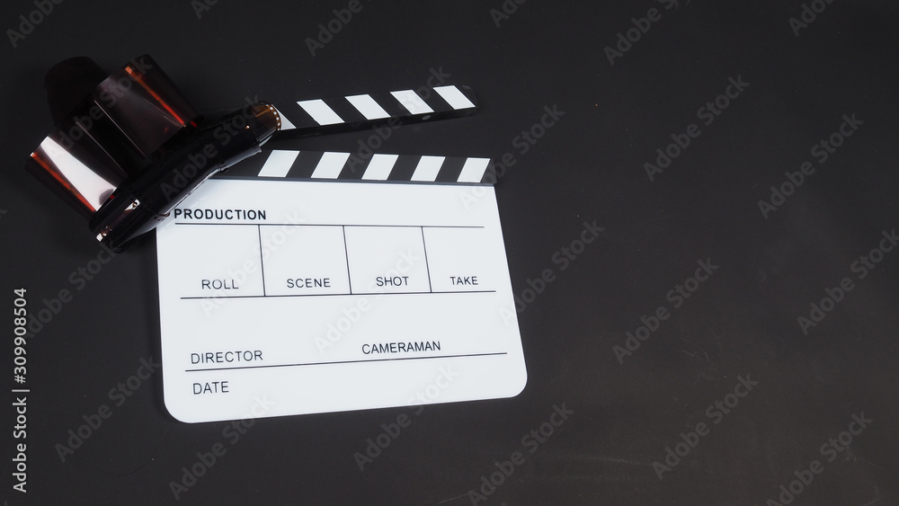 Film roll with Clapperboard or movie slate use in video production, cinema industry on black background.