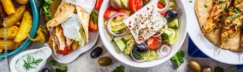 Photo Greek food: greek salad, chicken souvlaki, gyros and baked potato wedges on gray background, top view