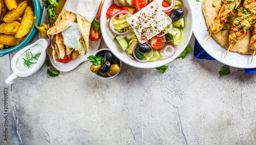 Photography Greek food: greek salad, chicken souvlaki, gyros and baked potato wedges on gray background, top view