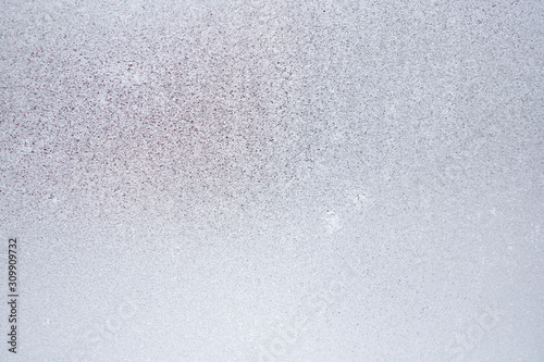 Ice and frost on a window pane in winter. Weather forecast: cold, frost, cooling. Abstract light blank background or wallpaper. Harsh season. Low contrast