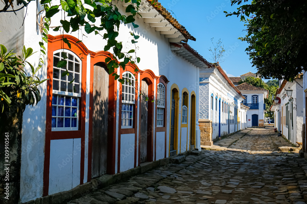 Typical cobblestone street with colorful colonial buildings in the late afternoon sun and shadows in historic town Paraty, Brazil