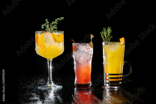 Three alcoholic cocktail with juice garnished gin, apricot brandy and orange juice. Beautiful New Year cocktails stand in a row.