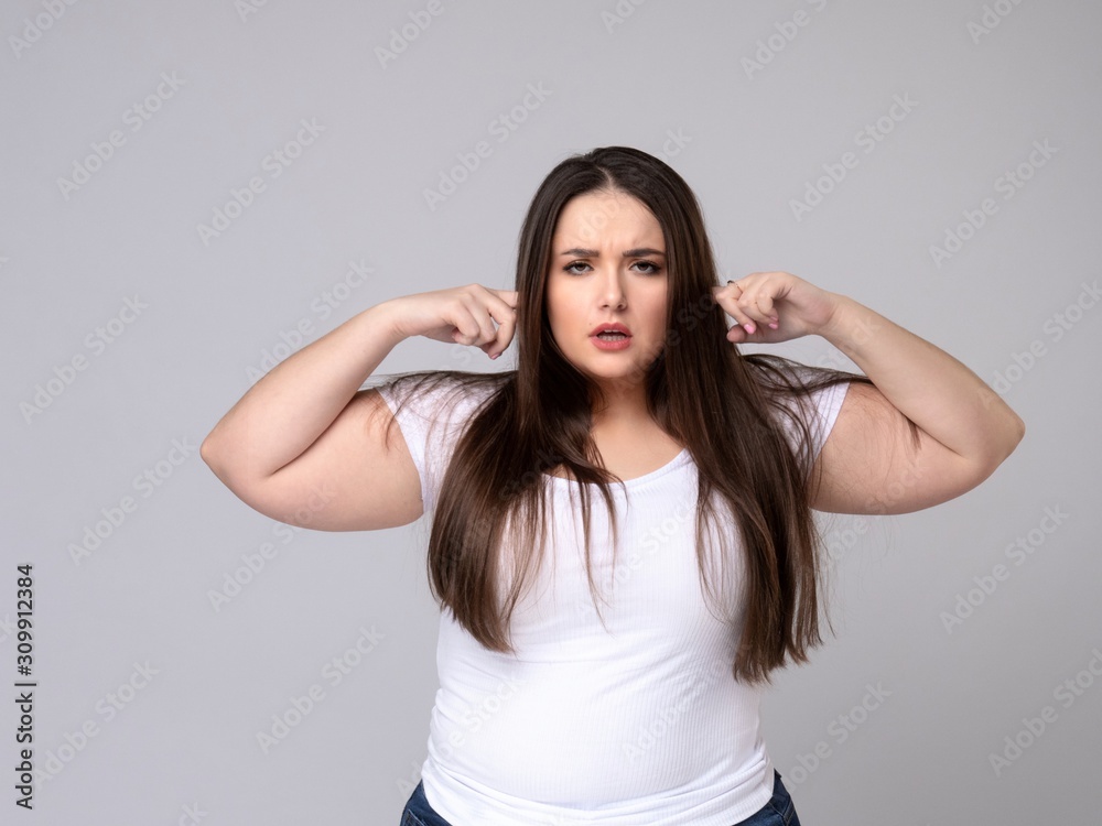 Aggressive Plus Size Model covers ears with fingers. Aggressive Plus Size Model covers ears with fingers.
