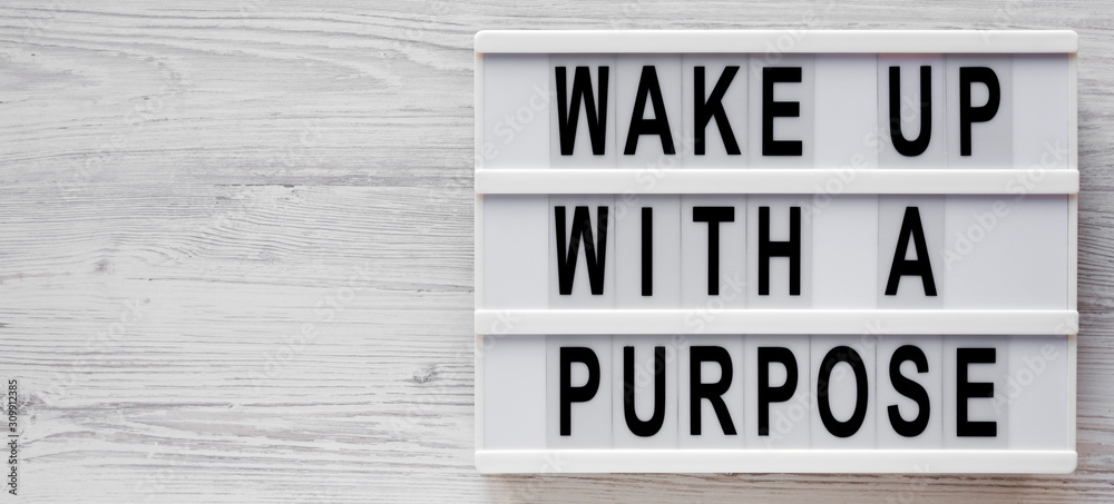 'Wake up with a purpose' words on a lightbox on a white wooden surface, top view. Overhead, from above, flat lay. Space for text. 'Wake up with a purpose' words on a lightbox on a white wooden surface, top view. Overhead, from above, flat lay. Space for text.