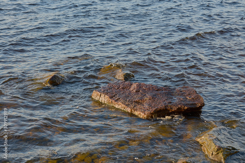 Rocks in water on the coast of a lake. Natural background. Copy space. 