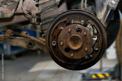 A close-up on the rear brake system of a car with hub on a lift in a vehicle repair workshop. Auto service industry.