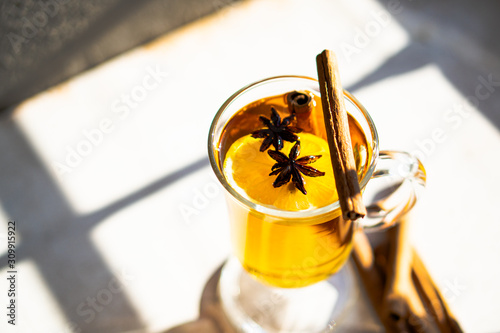 Hot winter drink with cinnamon and lemon on bright sunny day