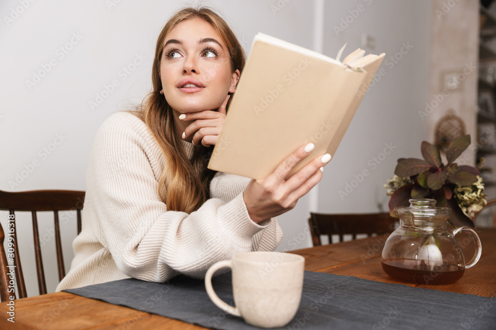 Image of nice caucasian woman reading book and drinking tea Image of nice caucasian woman reading book and drinking tea