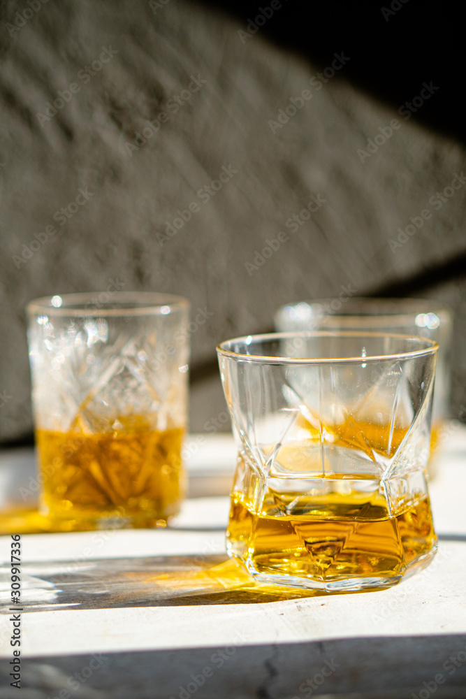 Whiskey in glasses on table in bright sunlight, yellow drink Whiskey in glasses on table in bright sunlight, yellow drink