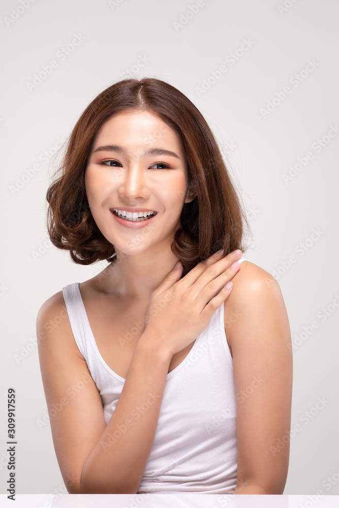 Beautiful Young Asian Woman with short hairs Touching Shoulder feeling so happy and cheerful with healthy Clean and Fresh skin,isolated on gray background,Beauty Cosmetology Concept